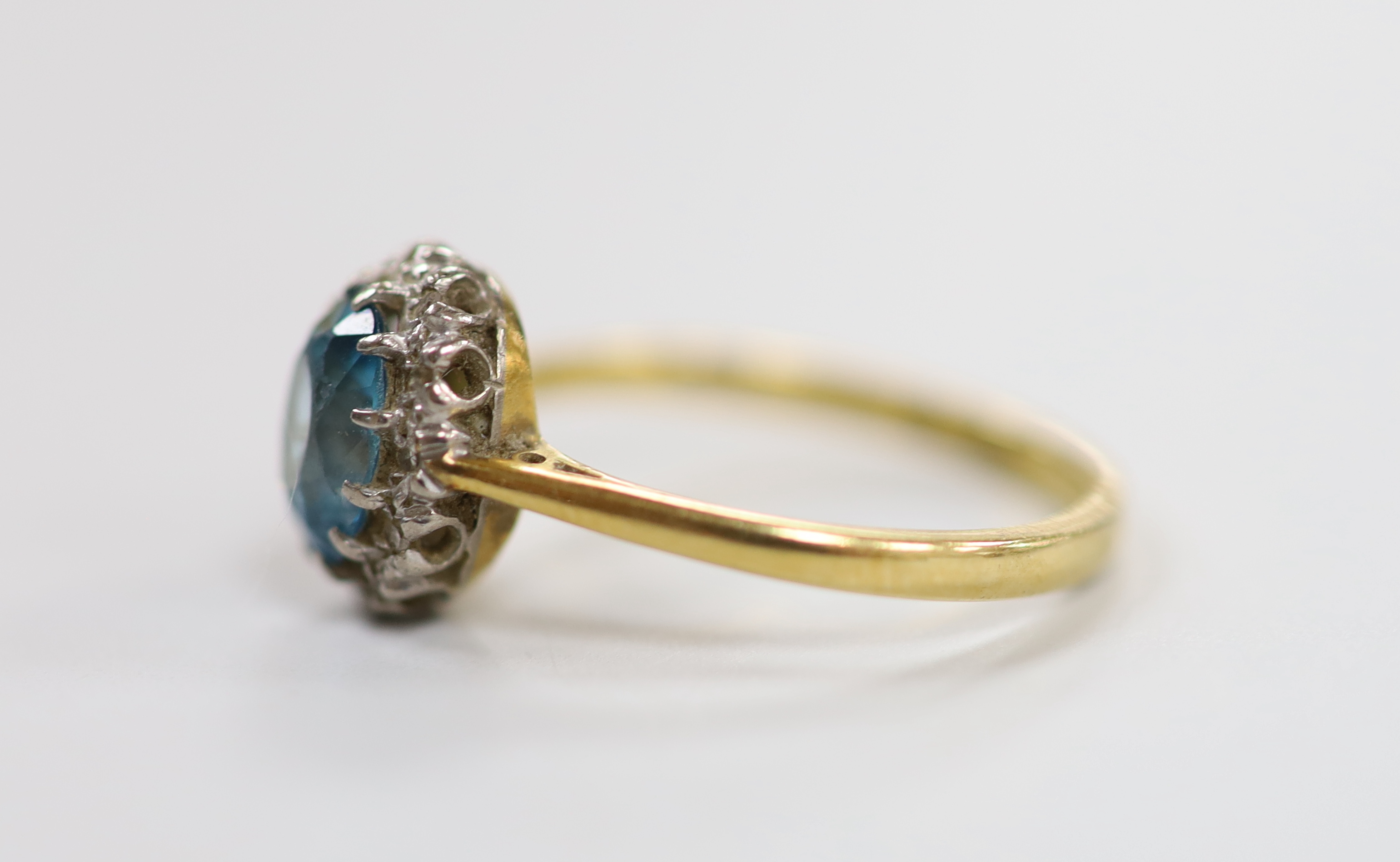An 18ct blue zircon and diamond chip set oval cluster ring, size N, gross weight 3.1 grams.